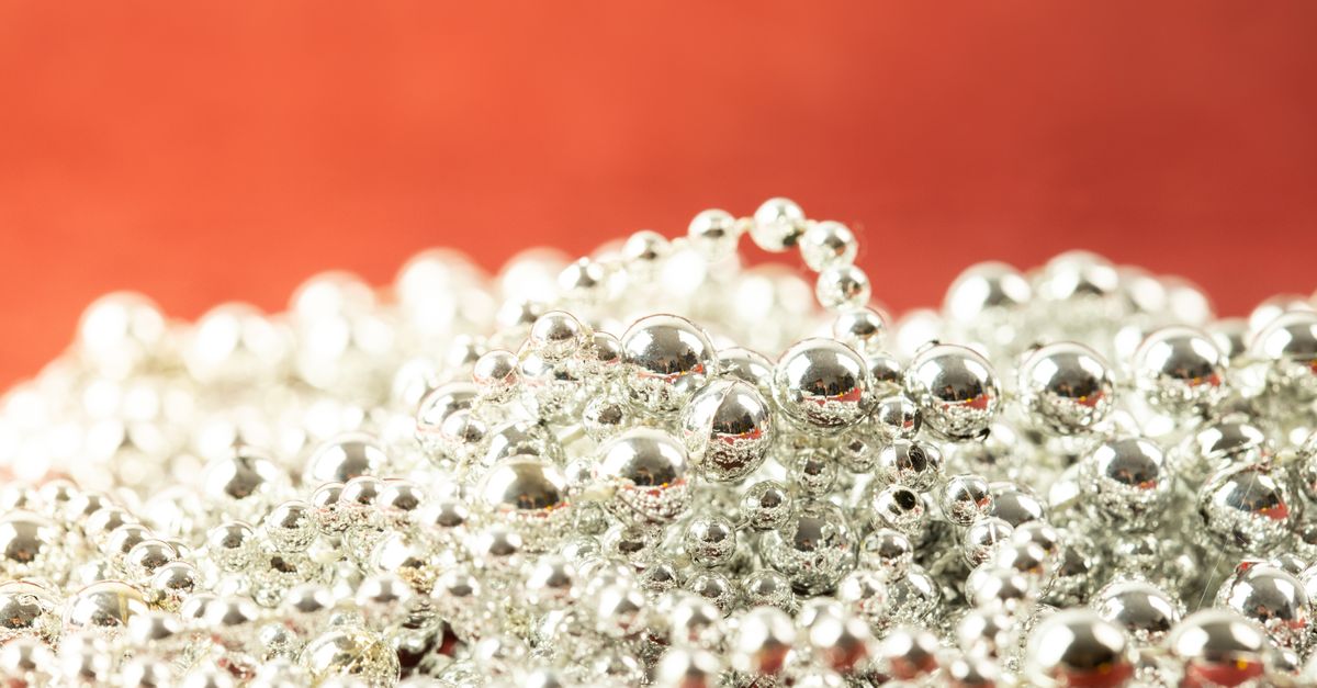 Close-up of shiny silver beads on a vibrant red background, symbolizing luxury and elegance.